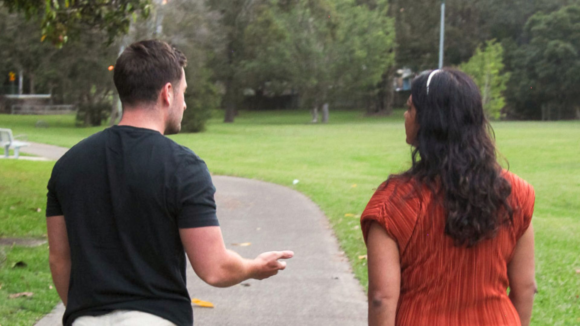 Two people walking together on a path in a green park, representing outdoor therapy and the mental health benefits of nature